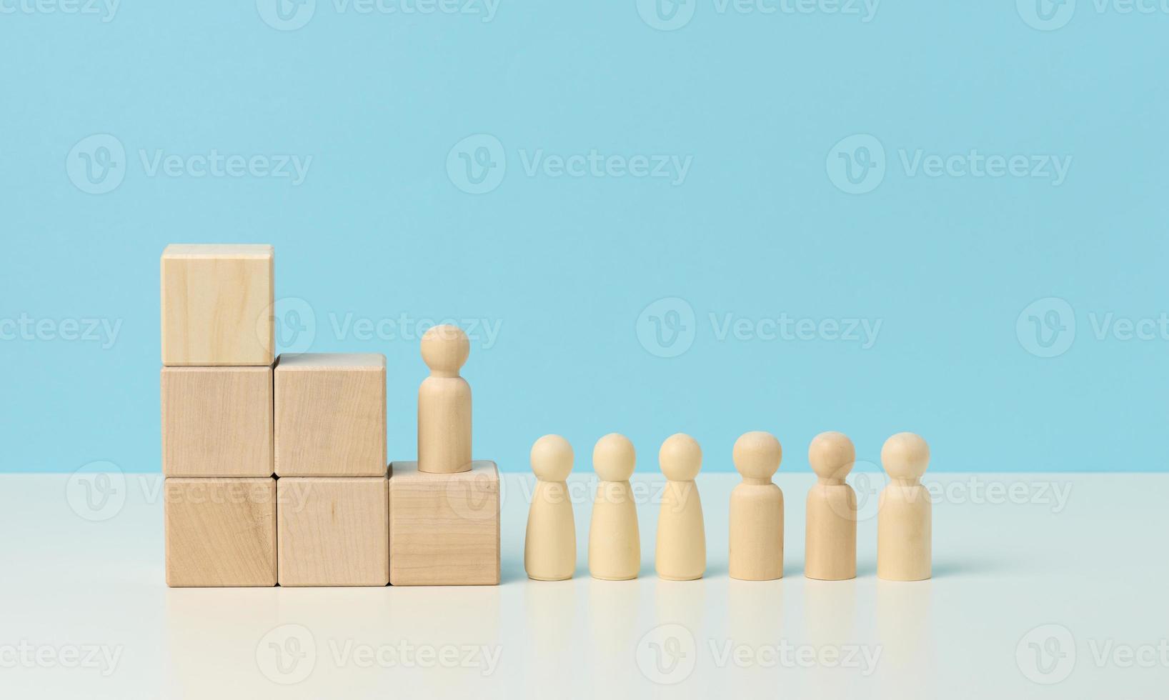 figuras de madeira de homens em uma escada feita de blocos. o conceito de progressão na carreira, começando no trabalho, alcançando metas foto