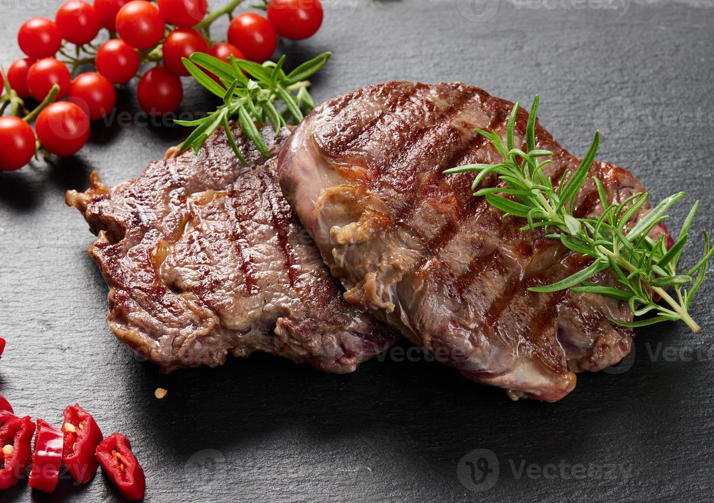 dois pedaços de bife frito em uma placa de ardósia preta, grau raro de cozimento. bife apetitoso foto