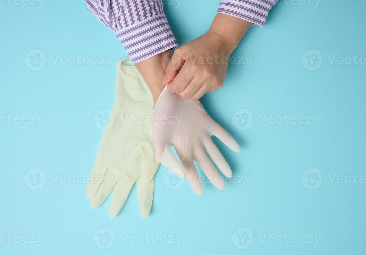 processo de colocar luvas de látex branco na mão sobre fundo azul, protetor de higiene foto