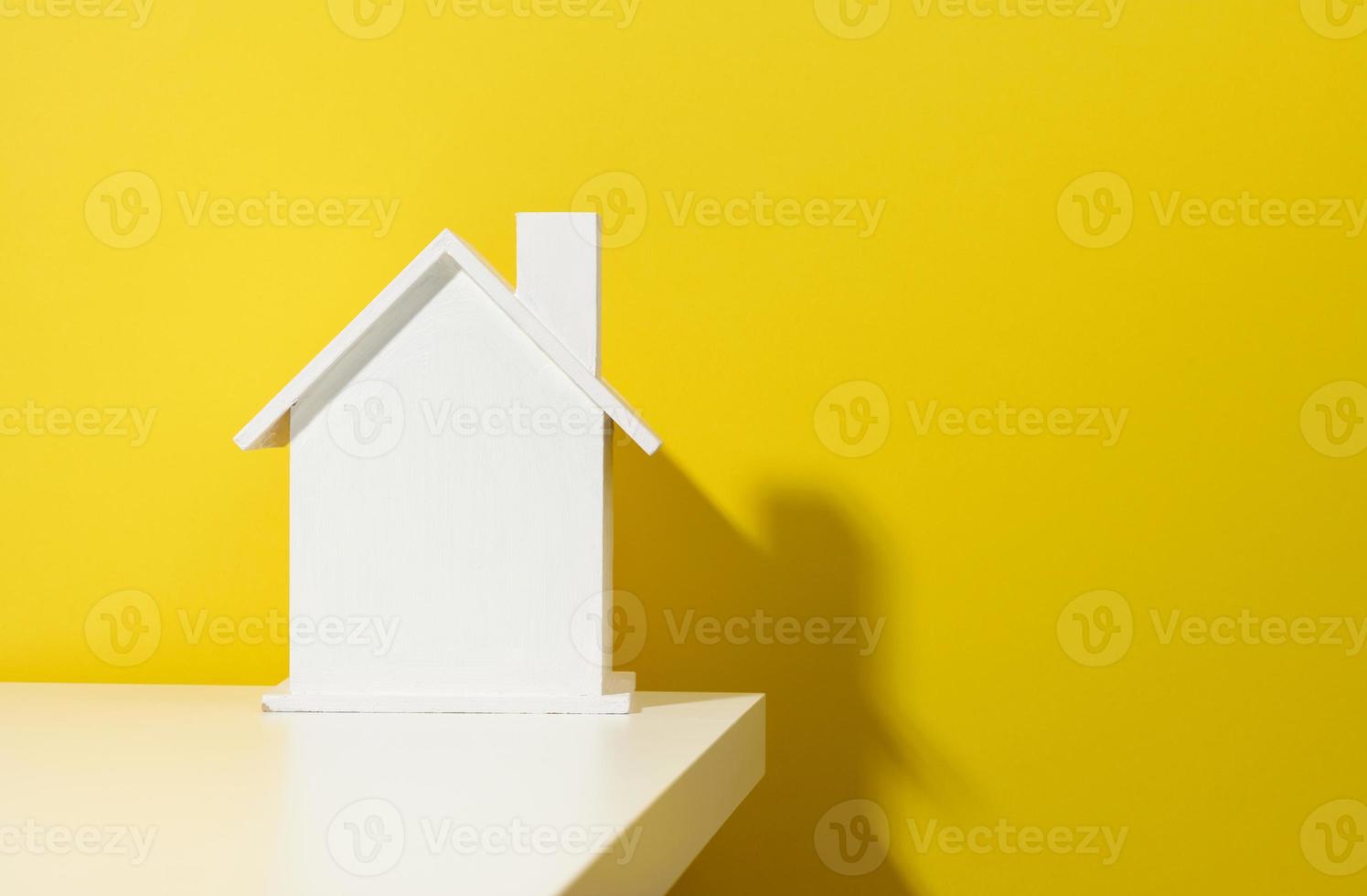 casa de madeira branca sobre um fundo amarelo. aluguel de imóveis, conceito de compra e venda. serviços de corretor de imóveis foto