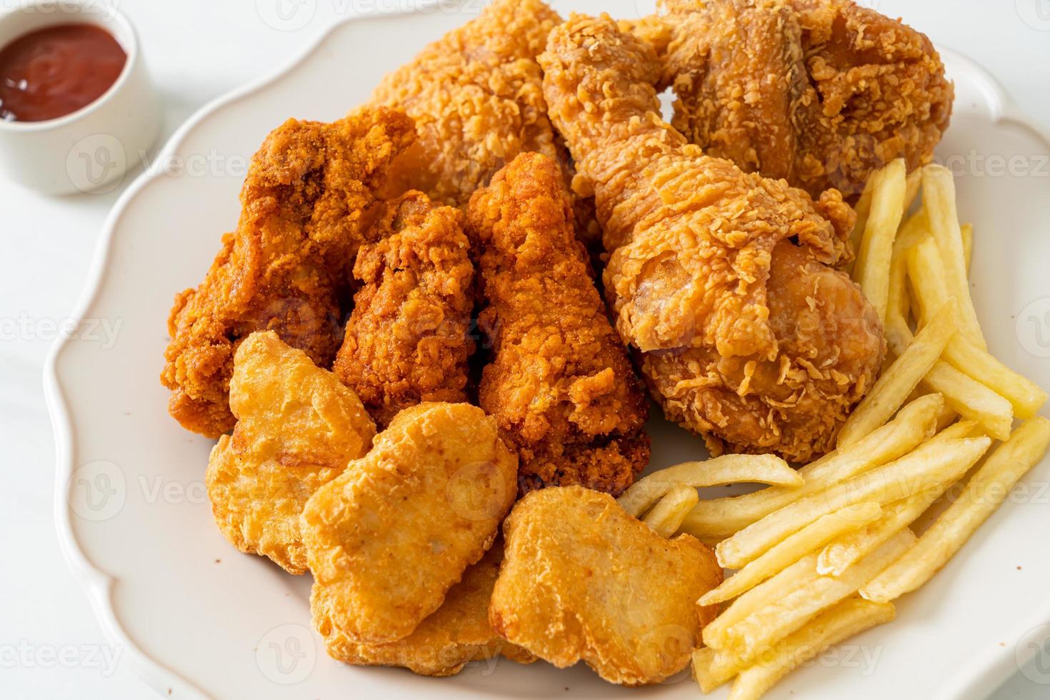 frango frito com batatas fritas e nuggets no prato foto