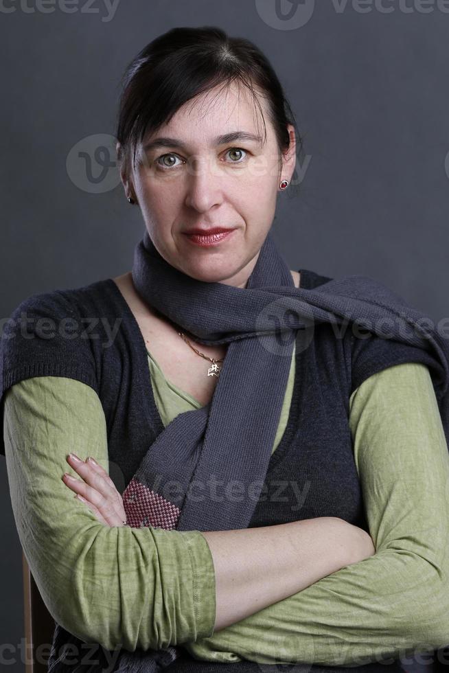 retrato de uma mulher de meia-idade em um fundo cinza. mulher quarenta anos olhando para a câmera. foto