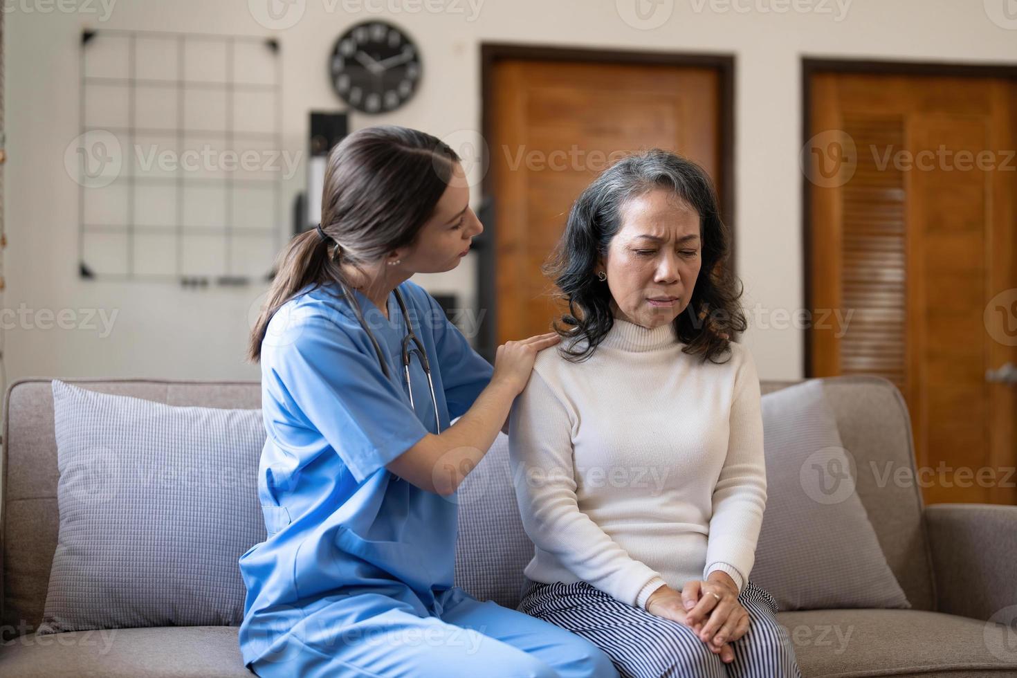 jovem médica inclinada para a frente para uma senhora idosa paciente segurando a mão nas palmas das mãos. apoiando a pessoa idosa encorajadora. foto