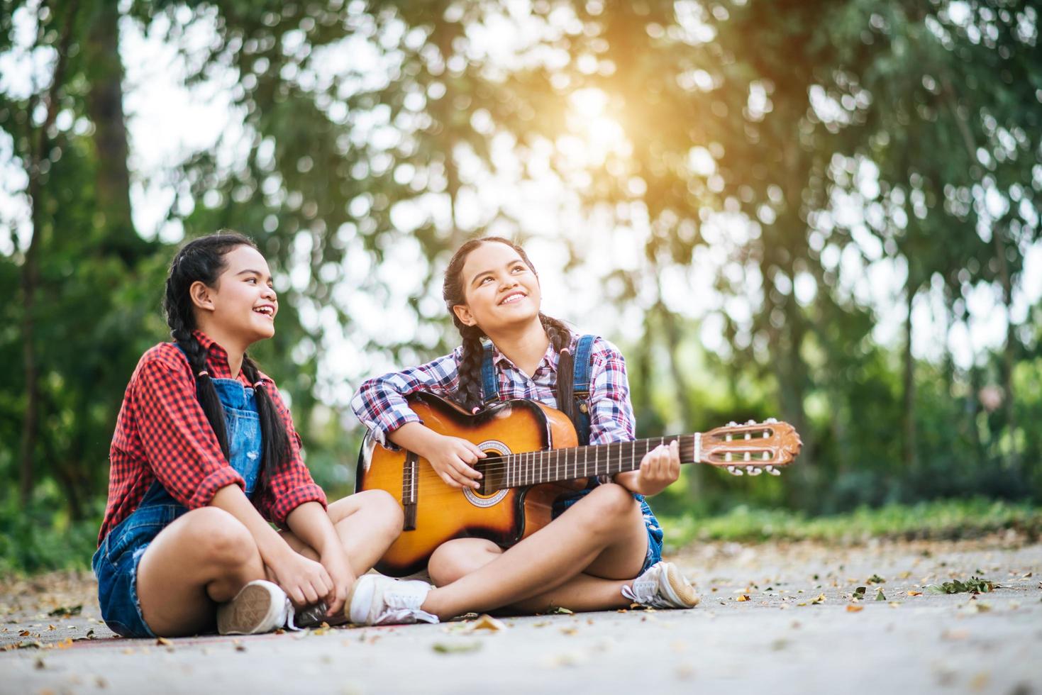 duas garotas relaxando e tocando violão foto