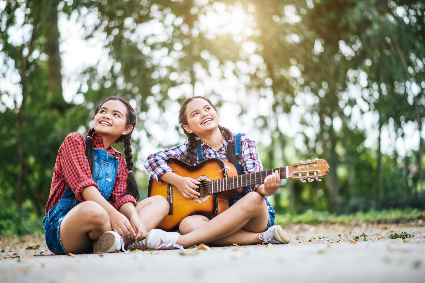 duas garotas relaxando e tocando violão foto