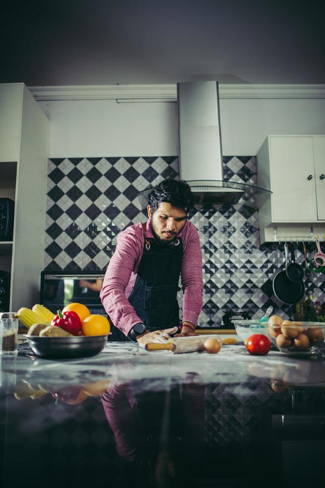 homem amassando massa de pizza caseira na cozinha foto