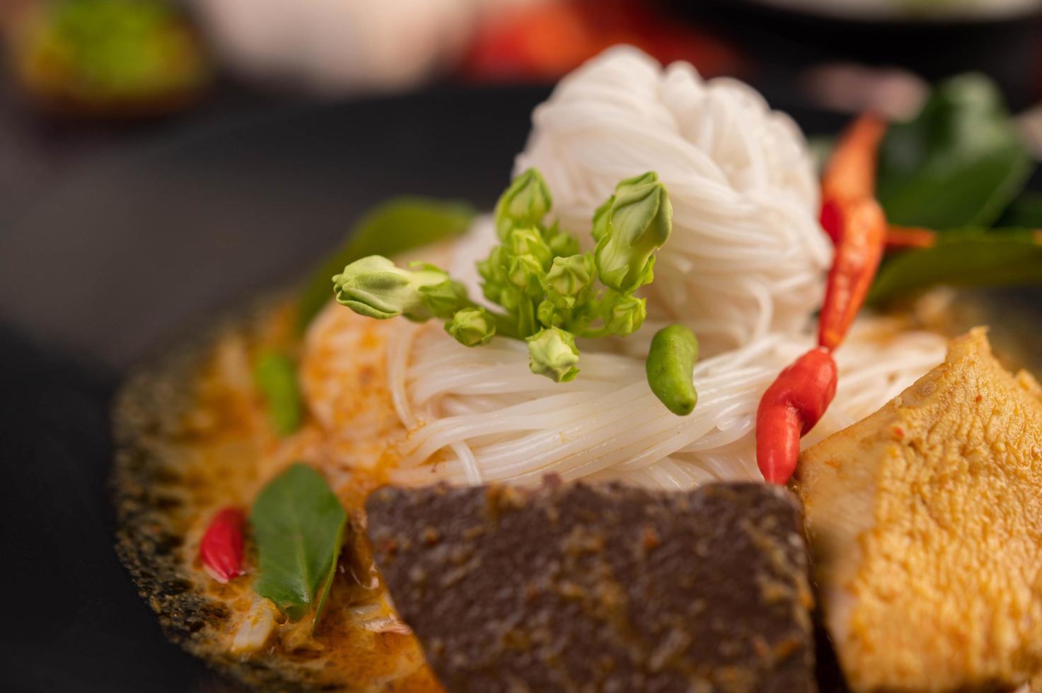 curry de frango em uma xícara preta com macarrão de arroz foto