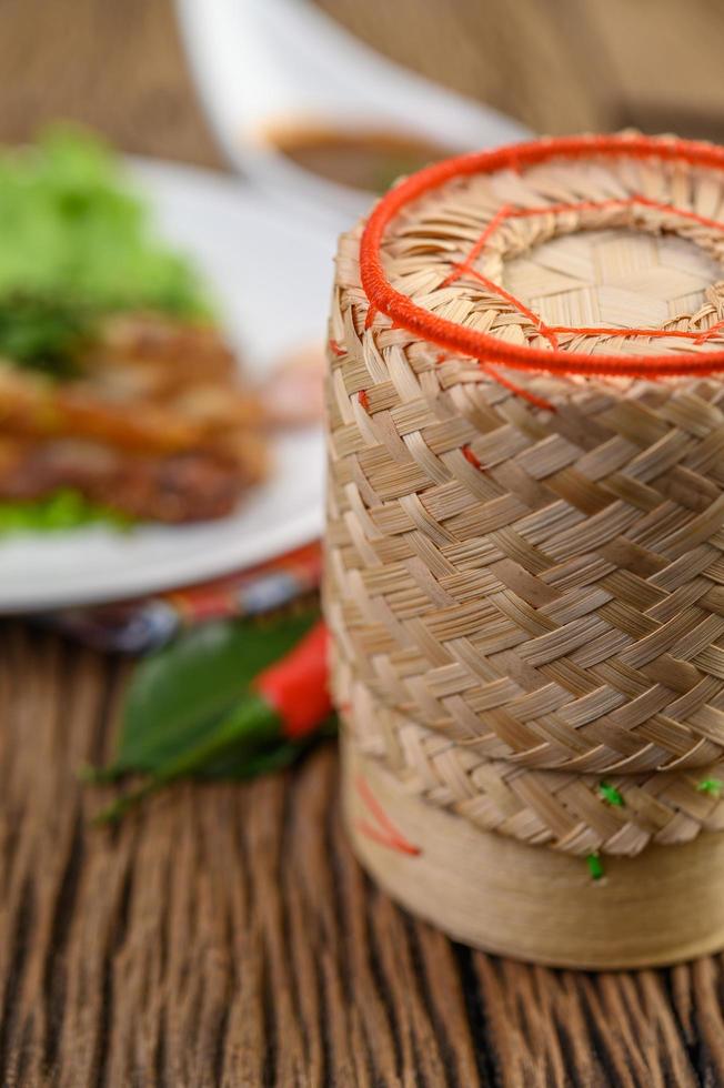 caixa de bambu para arroz pegajoso em uma mesa de madeira foto