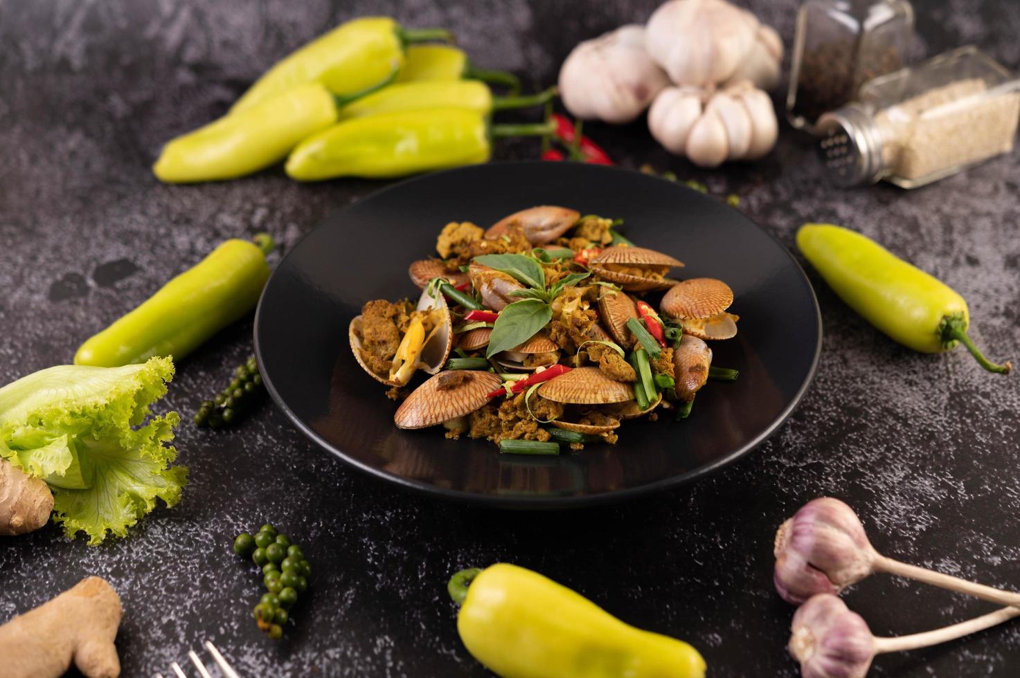 amêijoas fritas com curry em pó em um prato preto foto