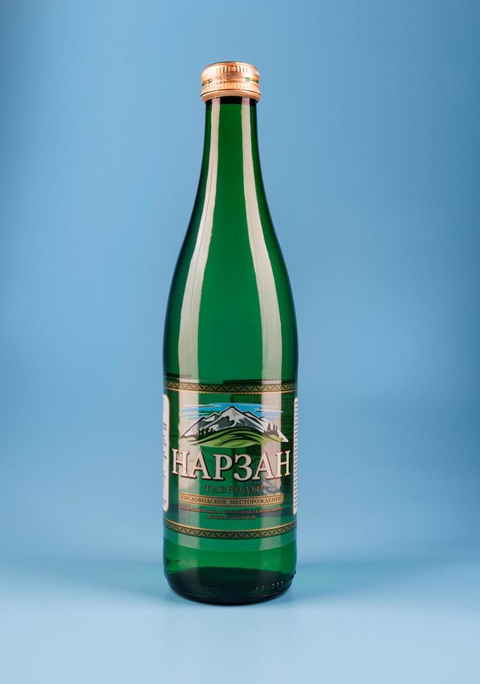 krasnoyarsk, rússia - 1 de novembro de 2022 garrafa de água mineral narzan sobre um fundo azul. água mineral em uma garrafa de vidro. foto