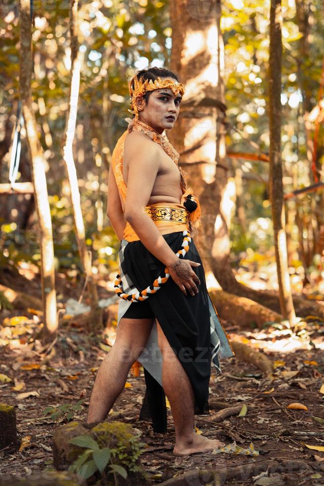 um homem tribal posa com maquiagem no rosto enquanto usa acessórios de ouro na cabeça e no pescoço foto