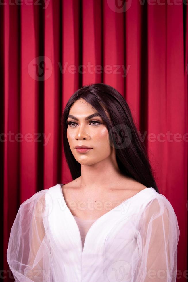 mulher asiática de luxo em um vestido branco com uma cortina vermelha ao fundo foto