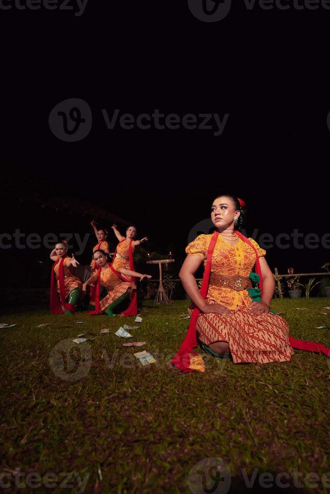 um grupo de dançarinos indonésios se apresentando no palco com um lenço vermelho e um vestido laranja tradicional dentro do festival foto