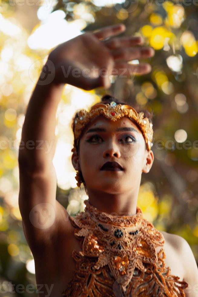 homem balinês posando com a mão enquanto usava uma coroa de ouro e sem camisa foto