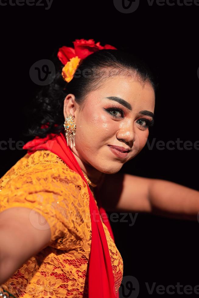 lindo rosto de uma mulher indonésia maquiada enquanto dançava uma dança tradicional em uma fantasia laranja durante o festival foto