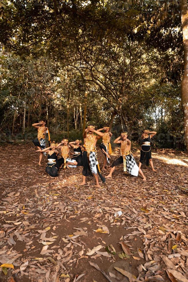 dança javanesa em trajes dourados enquanto usam uma pose de maquiagem juntos perto das folhas marrons foto