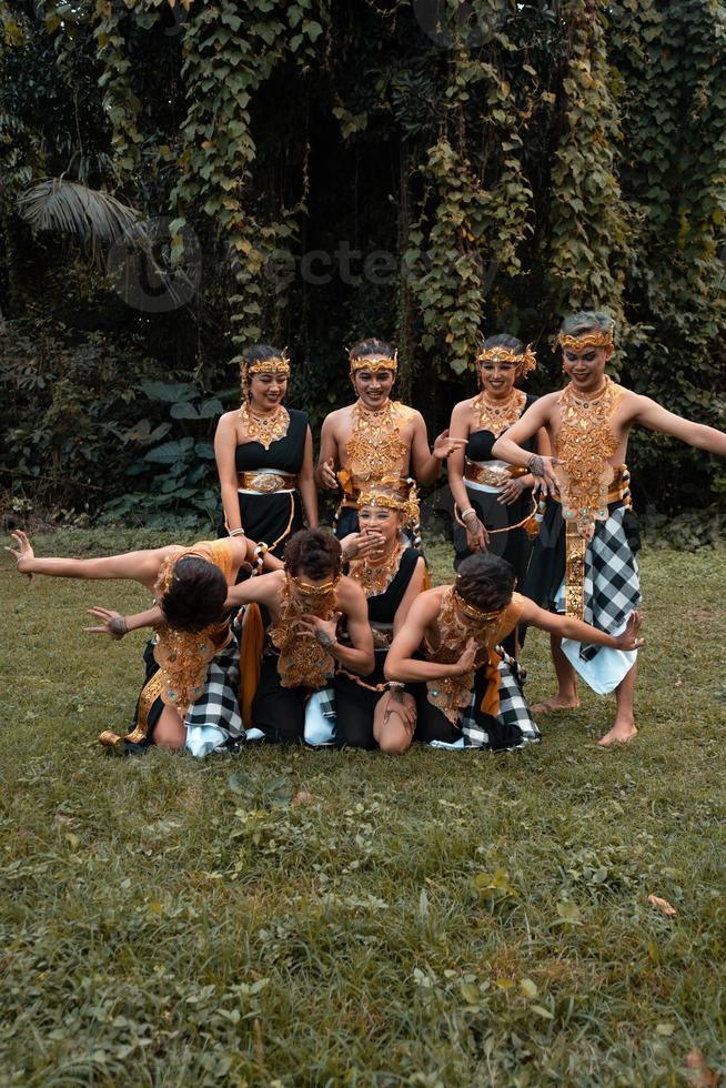 um bando de asiáticos se divertindo enquanto tiram uma foto com uma fantasia de dança dourada em frente à selva