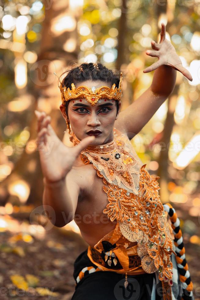 pose de dança de um homem balinês assustador com um colar de ouro e uma coroa em seu corpo sem camisa foto