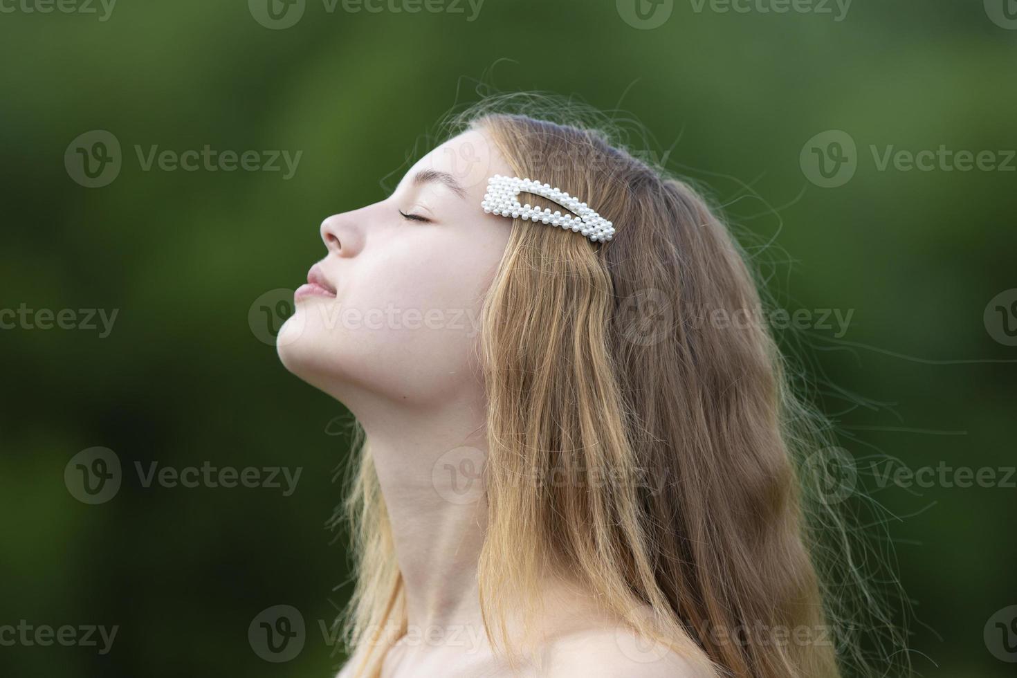 perfil de uma linda garota com cabelo comprido em um fundo de verão. foto