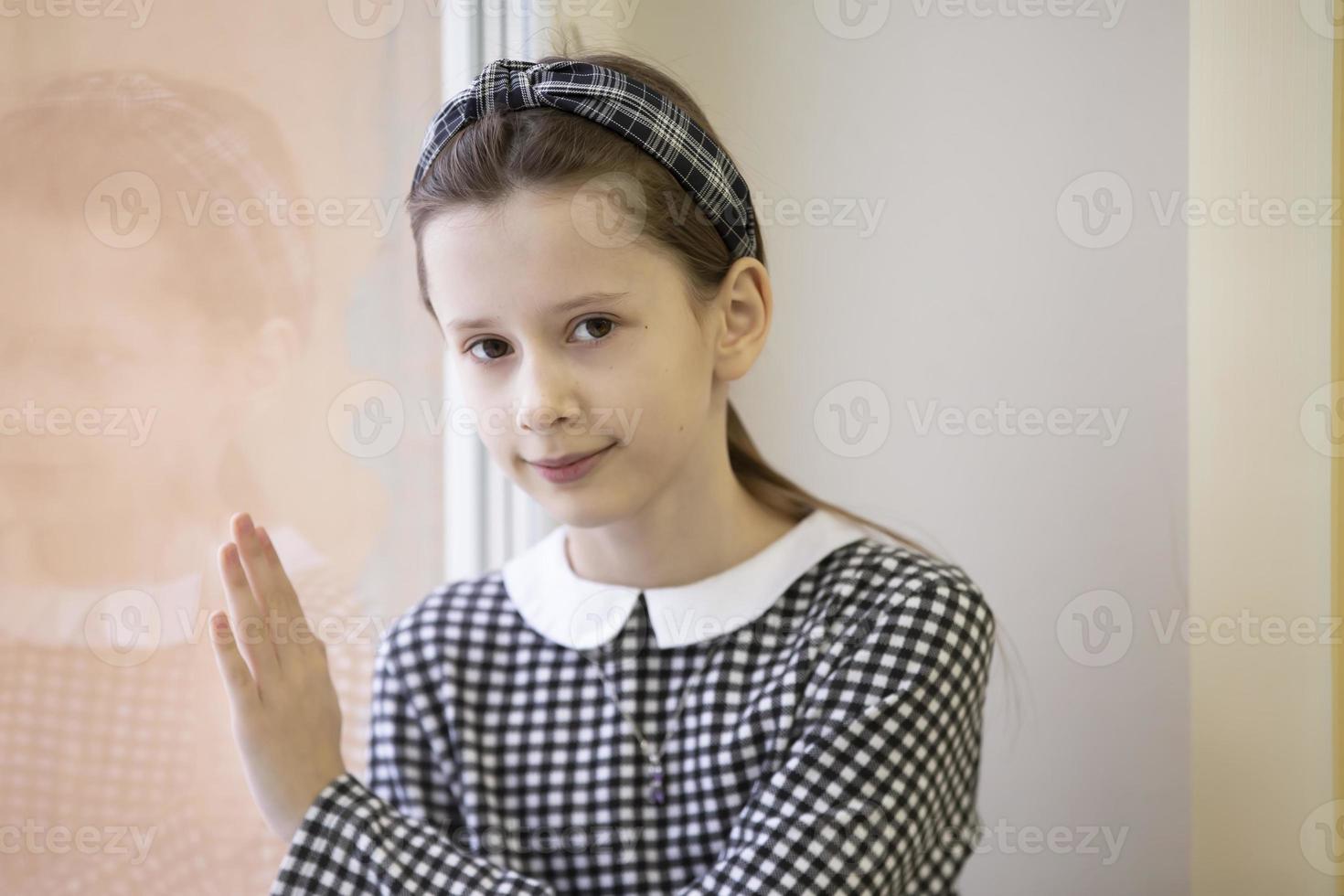 linda menina de dez anos. colegial na janela. foto