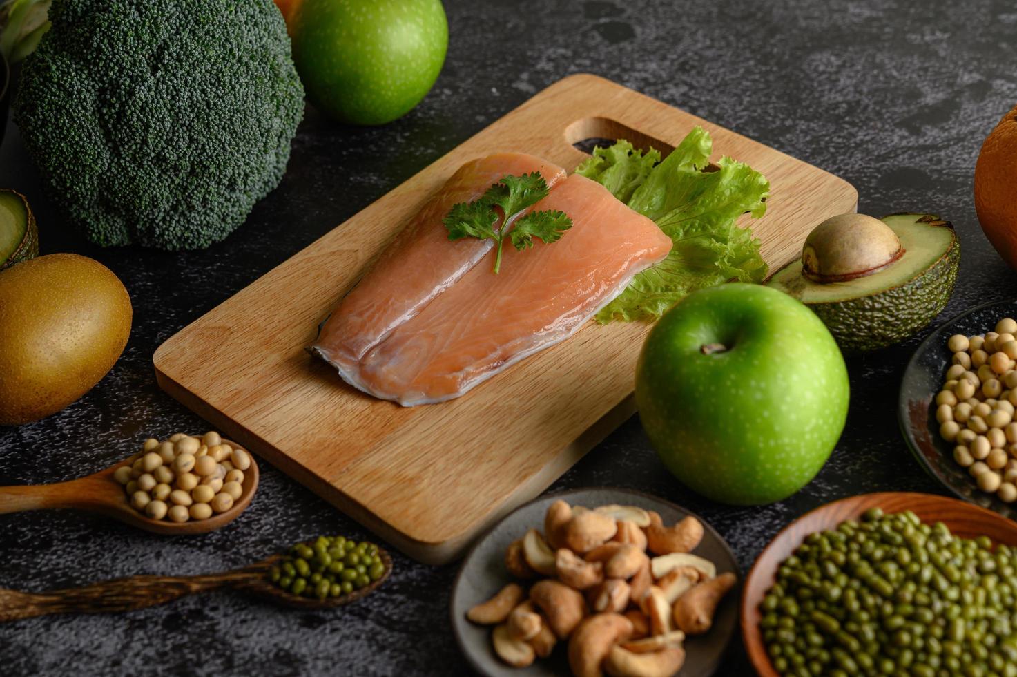 legumes, frutas e peixes salmão em uma tábua de madeira foto