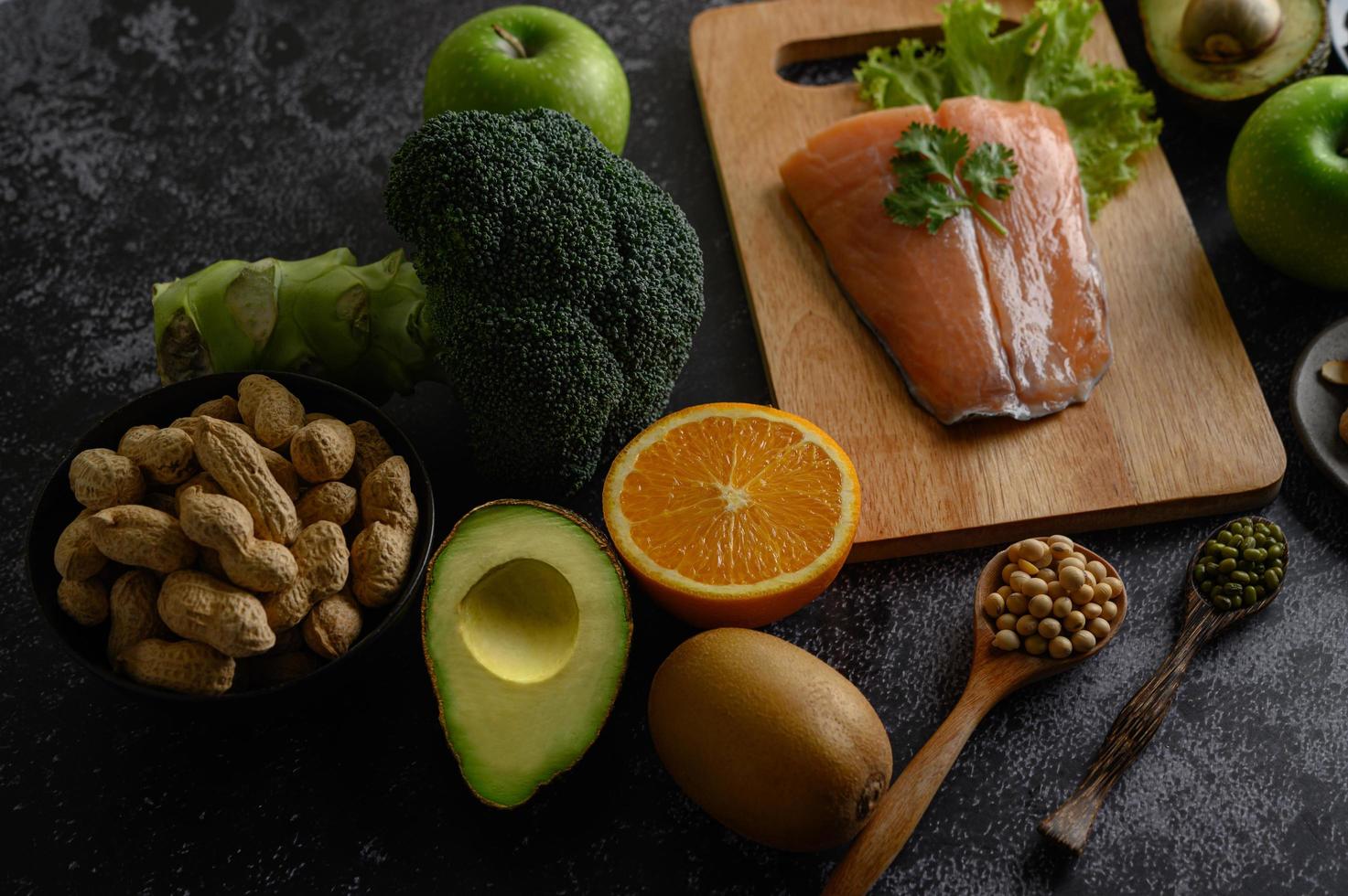 legumes, frutas e peixes salmão em uma tábua de madeira foto