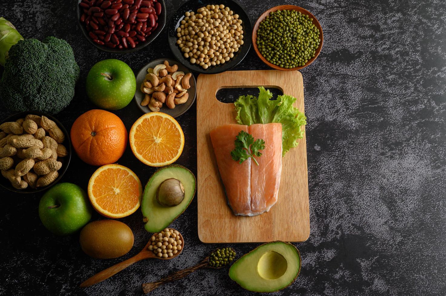 legumes, frutas e peixes salmão em uma tábua de madeira foto