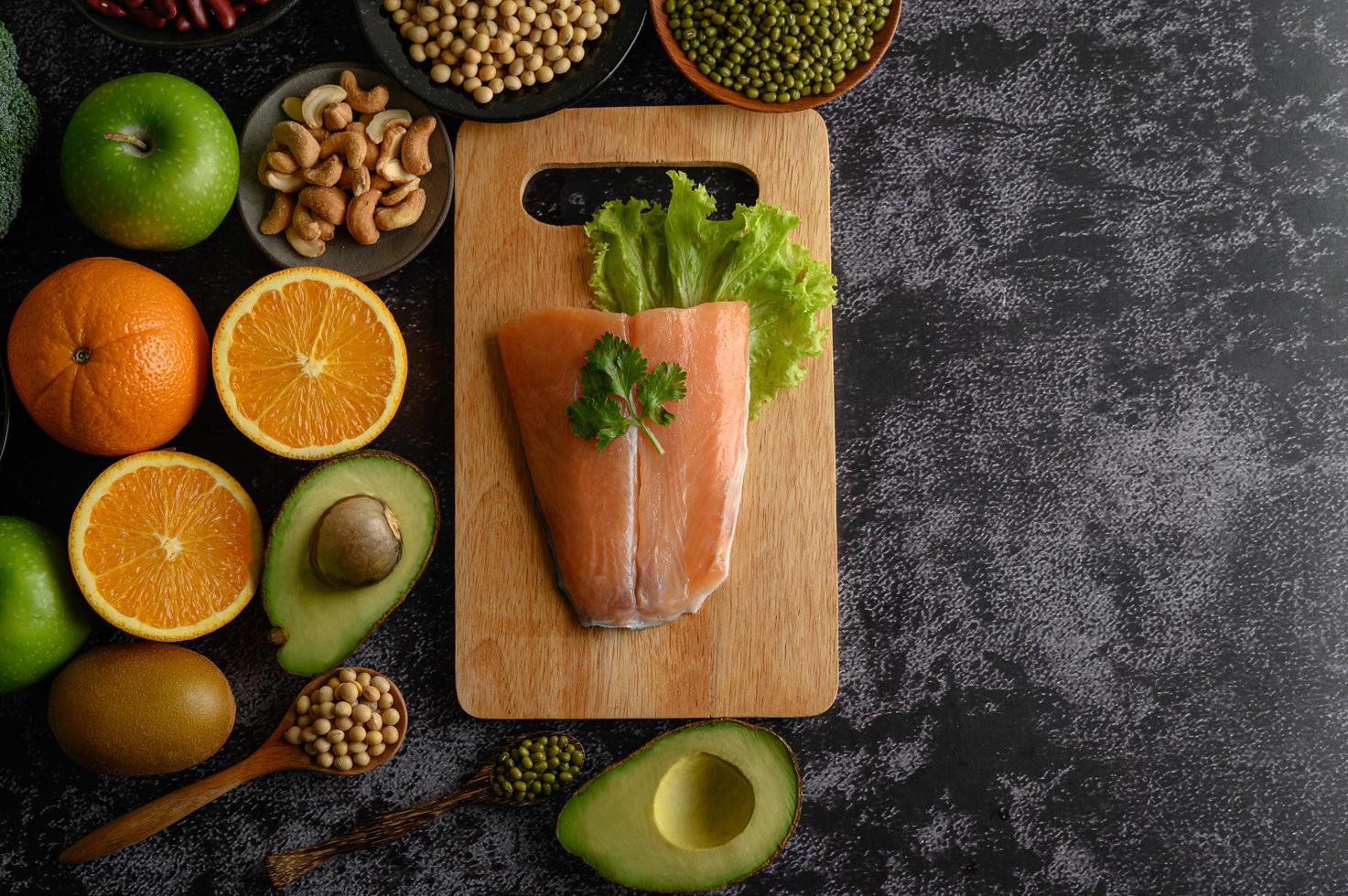 legumes, frutas e peixes salmão em uma tábua de madeira foto