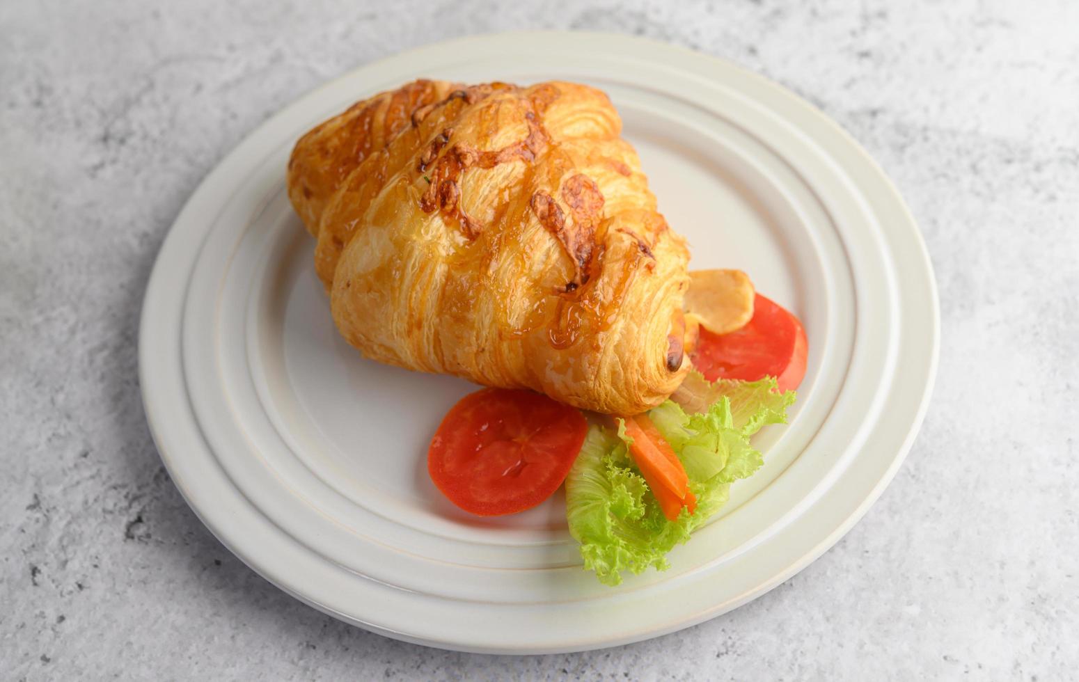 um croissant com cachorro-quente no prato branco foto