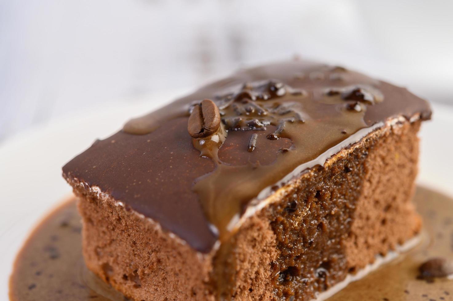 Bolo de chocolate coberto com café em um prato branco foto