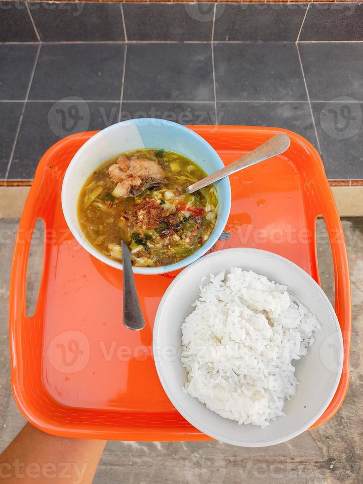 uma tigela de sopa e um prato de arroz em um prato largo laranja foto