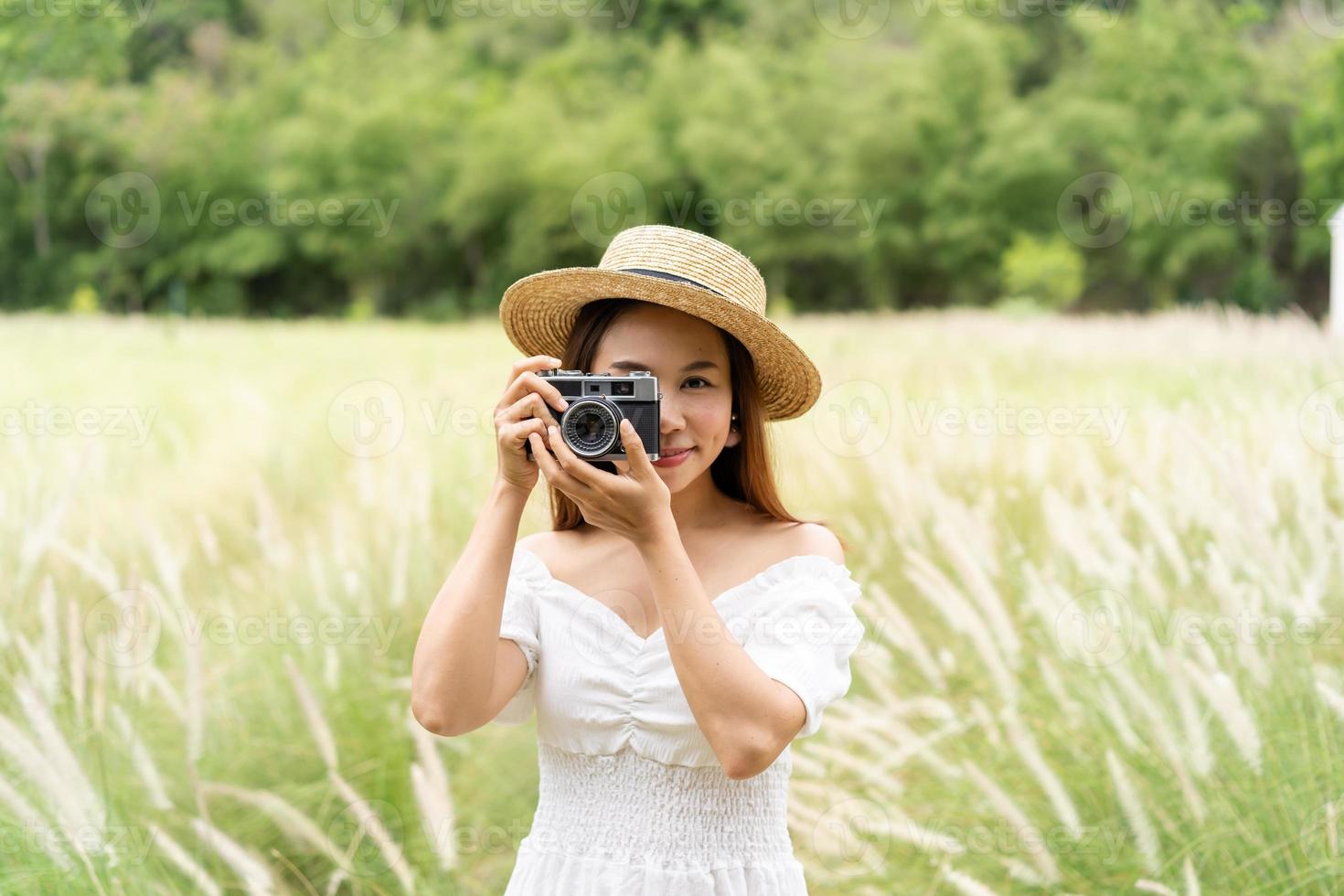 jovem mulher asiática fotografando e curtindo no campo de flores enquanto viajava no verão foto