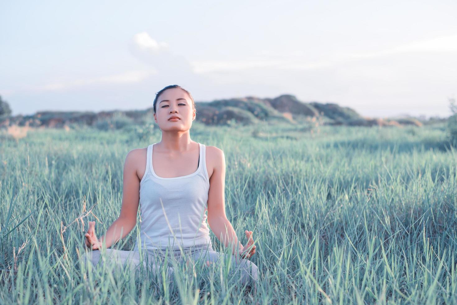 mulher de ioga na postura de lótus em um prado ensolarado foto