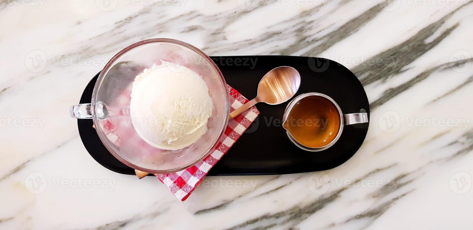 postura plana de copo de sorvete de baunilha com colher de chá de latão colocada em algodão xadrez vermelho com caneca inoxidável de café expresso em bandeja preta na mesa de mármore branco com espaço para cópia - sobremesa de café affogato foto