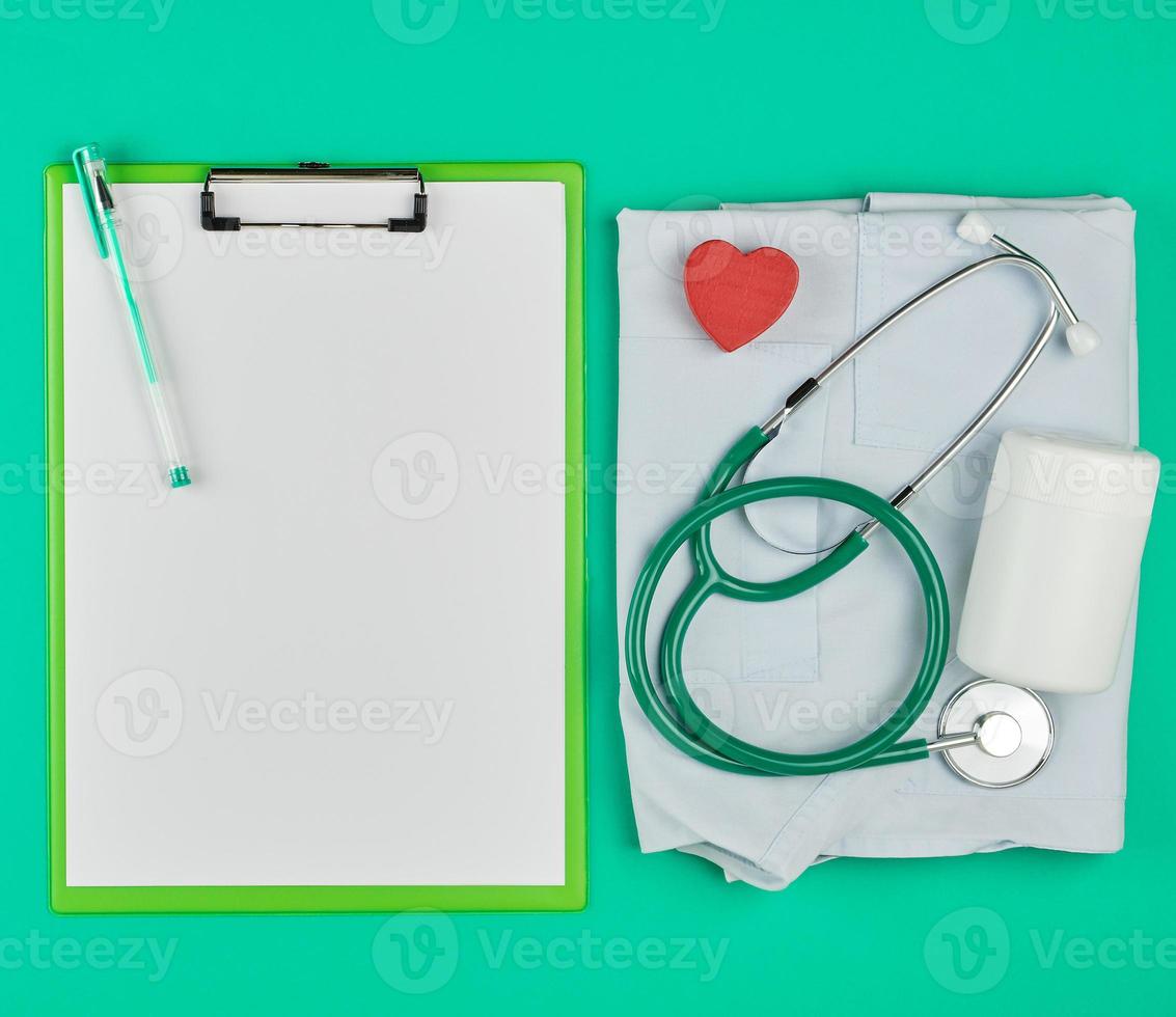lençóis brancos vazios e um estetoscópio médico sobre um fundo verde foto