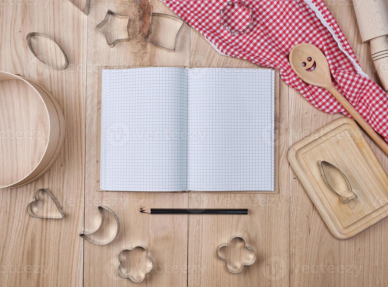 caderno aberto em branco na linha e acessórios de cozinha de madeira foto