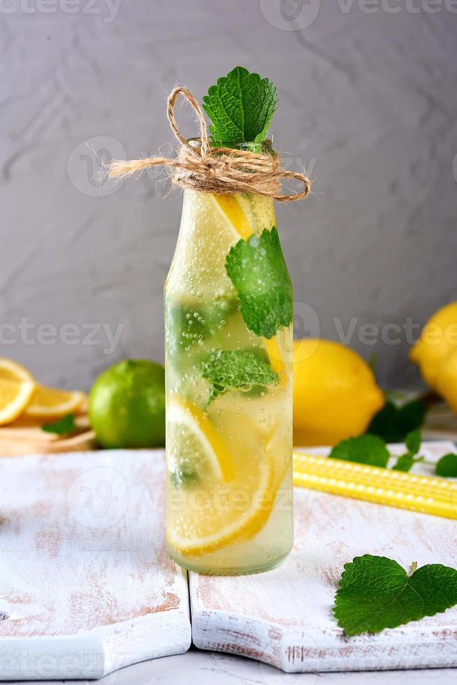 limonada com limões, folhas de hortelã, limão em uma garrafa de vidro foto