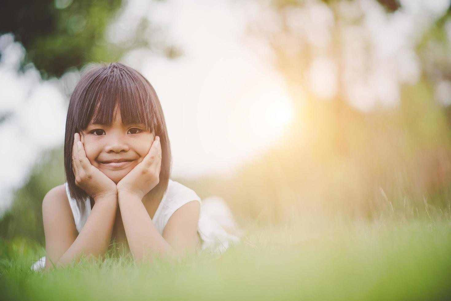 menina deitada confortavelmente na grama e sorrindo foto