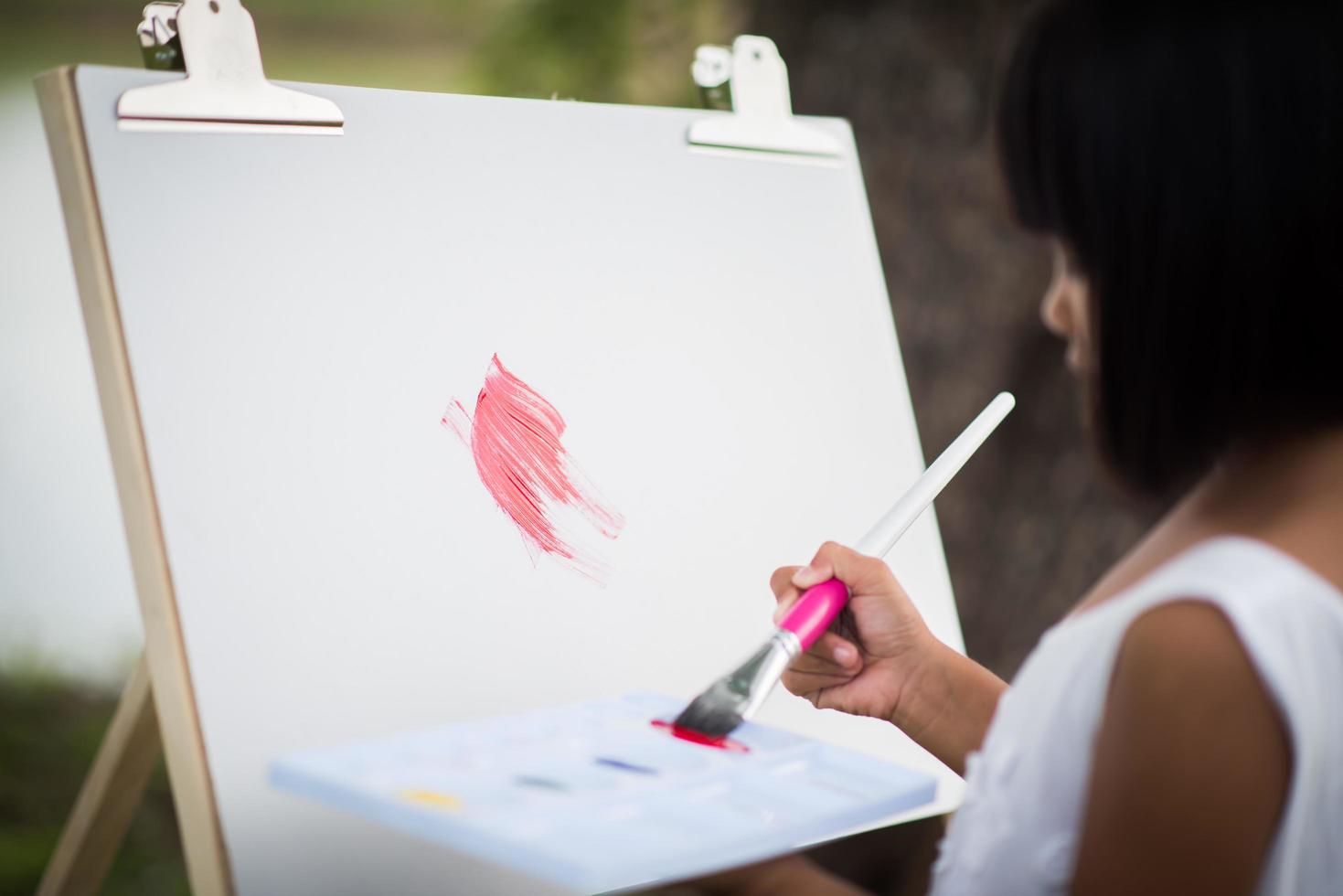 menina artista pintando um quadro no parque foto