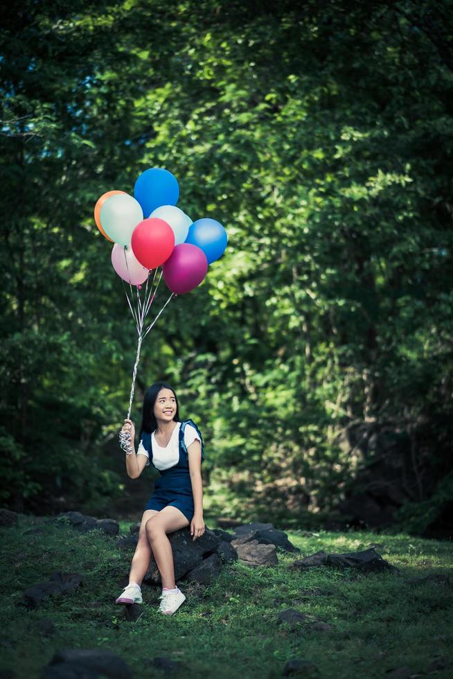 jovem segurando balões coloridos na natureza foto