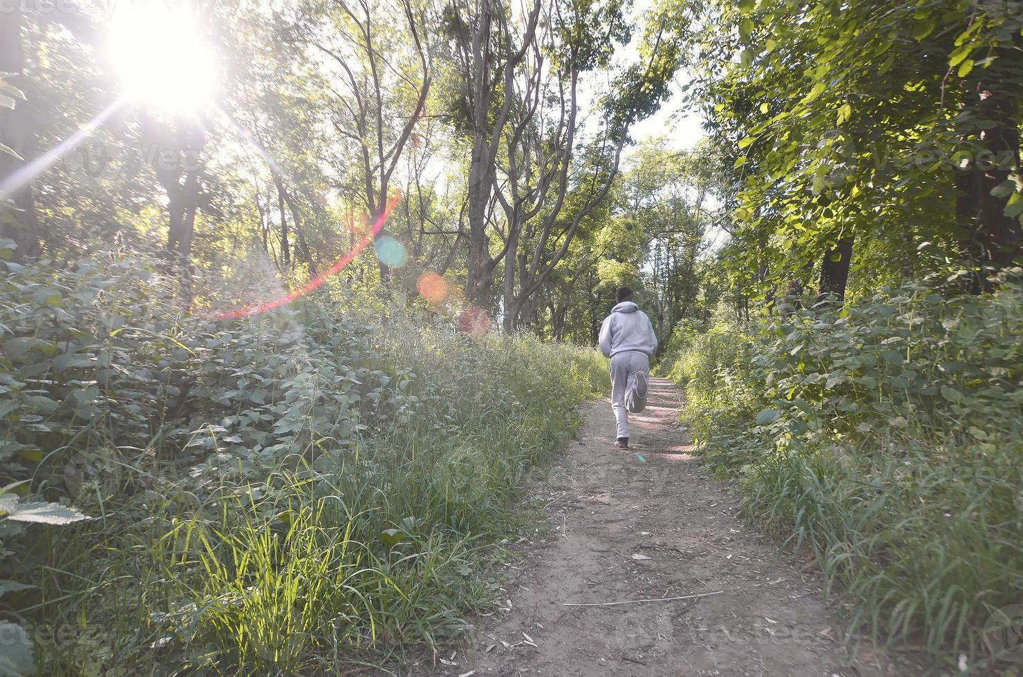 um jovem em um terno esportivo cinza corre ao longo do caminho entre os foto