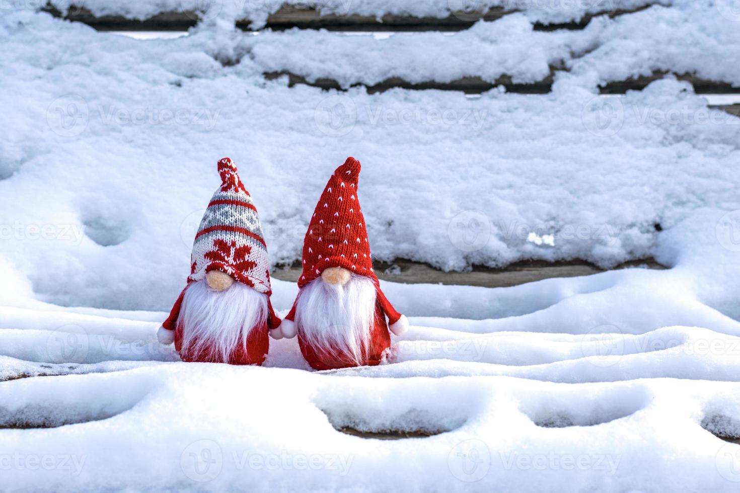 cartão de férias de natal gnomos escandinavos fofos com chapéu vermelho e barba branca no banco de inverno nevado conto de fadas queda de neve inverno olá dezembro, janeiro, conceito de fevereiro feliz ano novo, natal foto