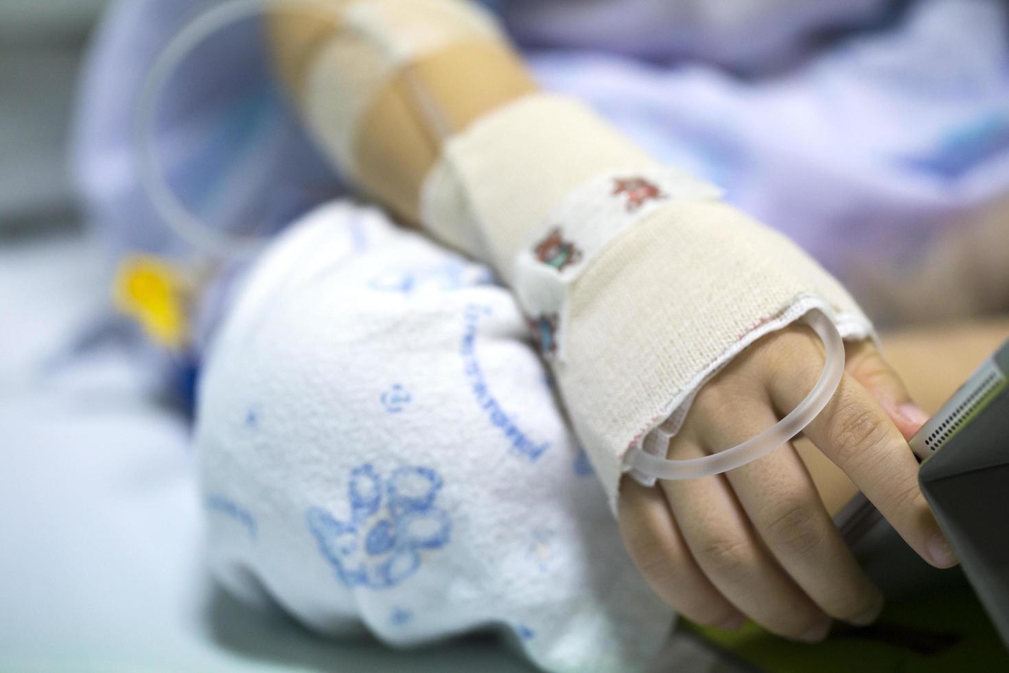 criança doente no hospital com iv no braço foto