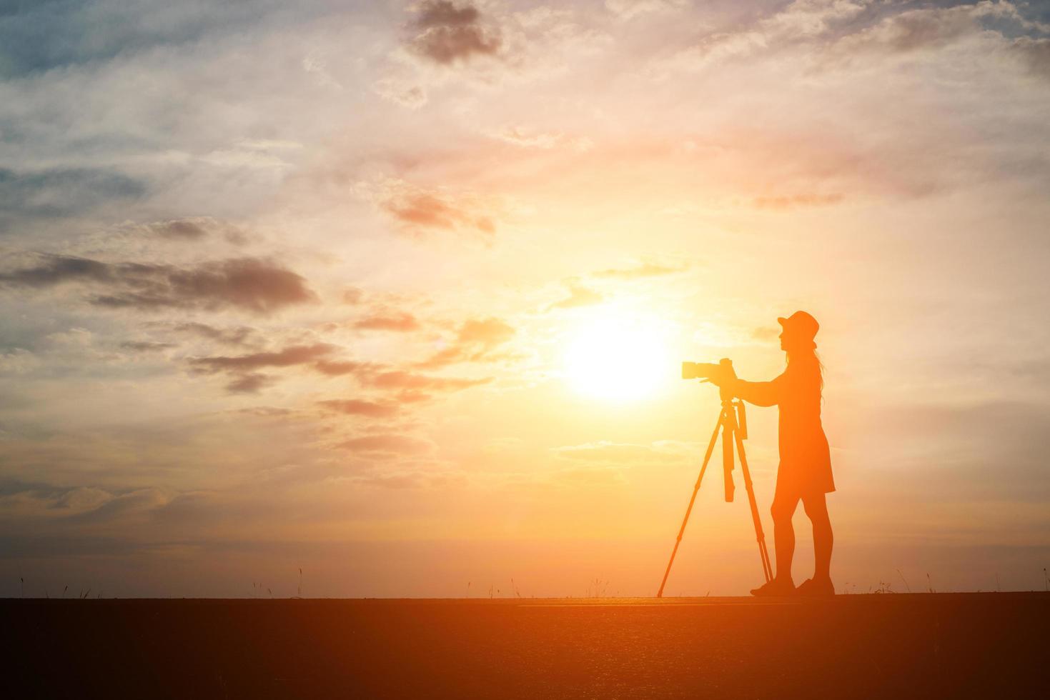 silhueta de um fotógrafo fotografando ao pôr do sol foto