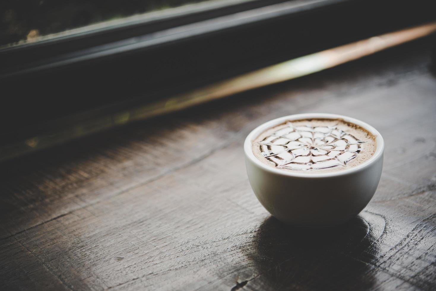 uma xícara de café em uma mesa de madeira foto