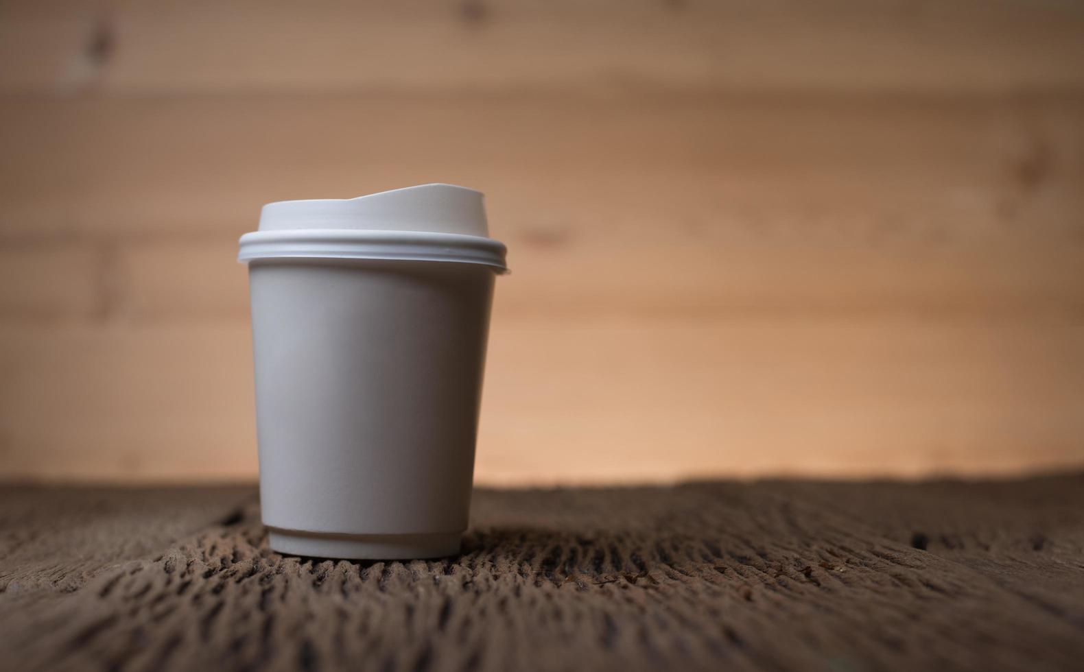 xícara de café de papel em branco na mesa de madeira foto