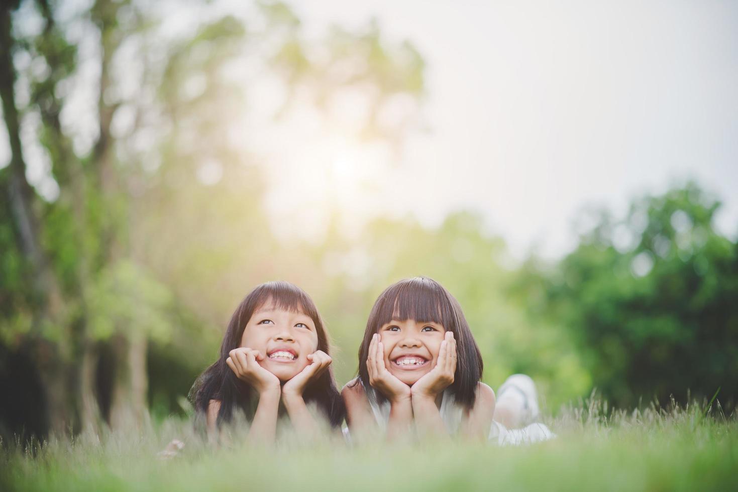 meninas deitadas confortavelmente na grama e sorrindo foto