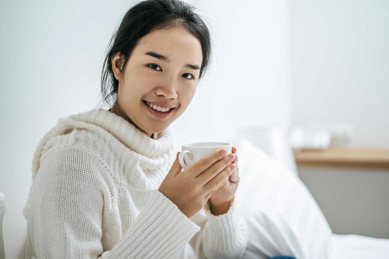 jovem segurando uma xícara de café na cama foto