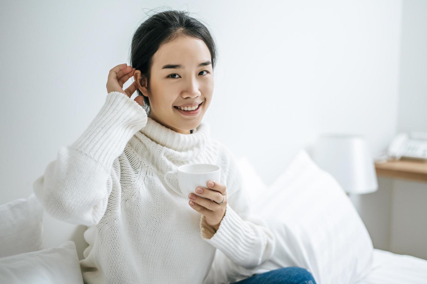 jovem segurando uma xícara de café na cama foto