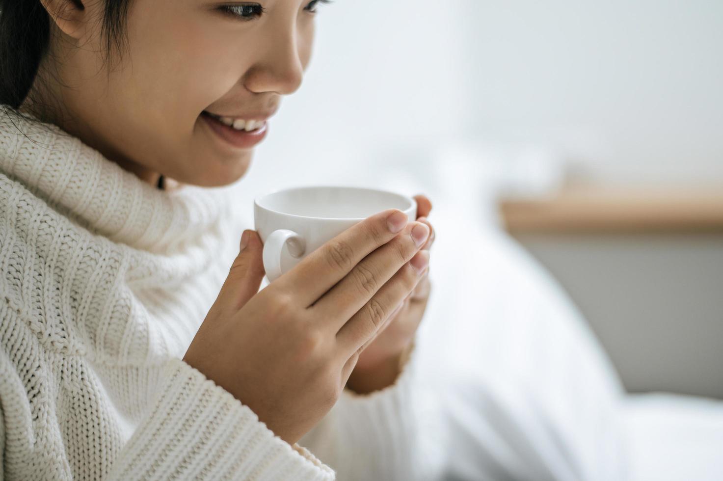 jovem segurando uma xícara de café na cama foto